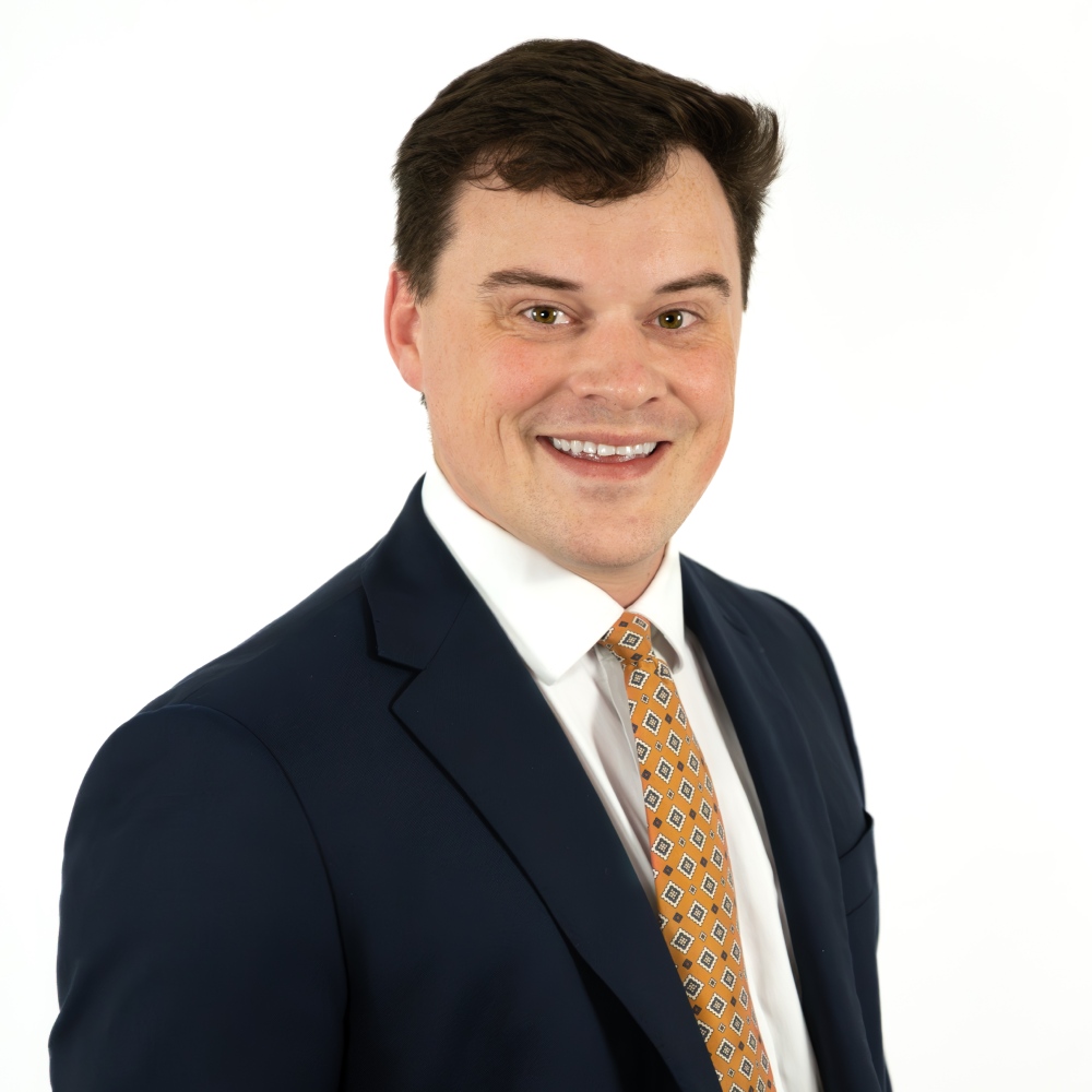 a man wearing a suit and tie smiling at the camera