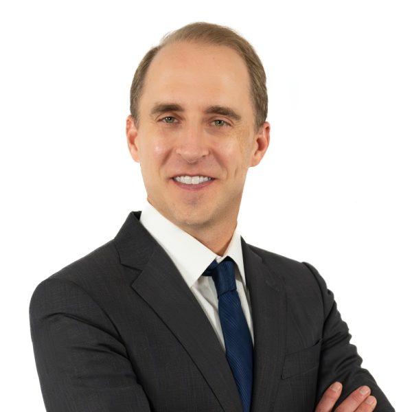 A Man Wearing A Suit And Tie Smiling At The Camera