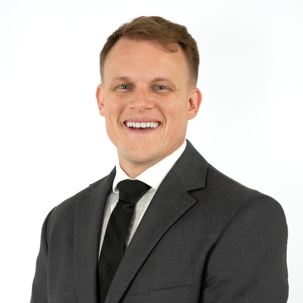 a man wearing a suit and tie smiling at the camera