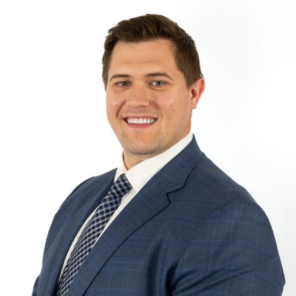 A Man Wearing A Suit And Tie Smiling At The Camera