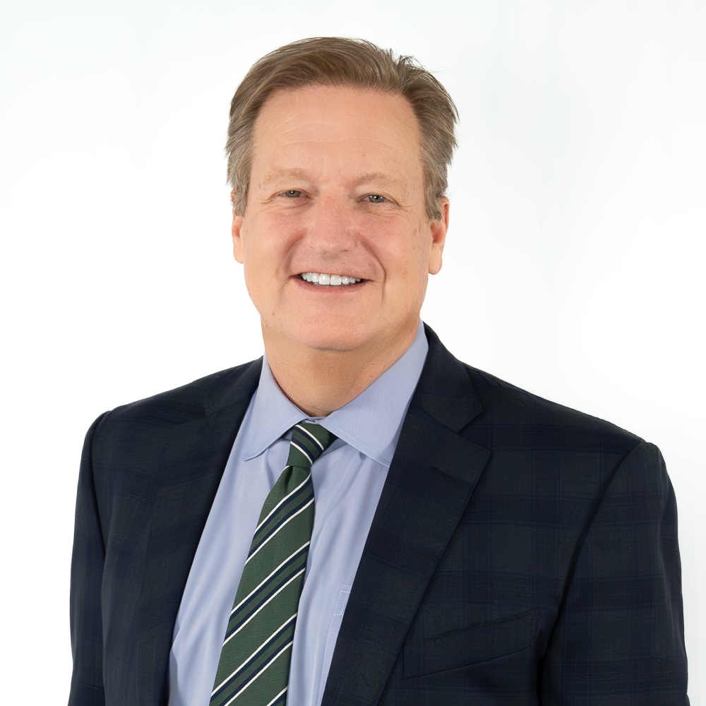 a man wearing a suit and tie smiling at the camera