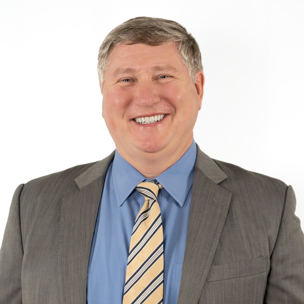 a man wearing a suit and tie smiling at the camera